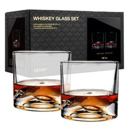 Two clear glass whiskey glasses containing amber-colored liquid and ice cubes. The glasses have a simple, elegant design.