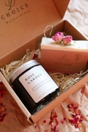 Floral-patterned gift box containing a rose-scented candle and a bottle of rose wine.