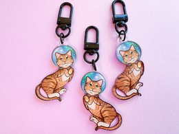 Tabby cat astronaut keychain with cartoon-style illustration of a cat wearing a spacesuit.