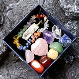 Colorful assortment of crystals, stones, and a heart-shaped pendant in a black box. Includes various shapes, colors, and materials for meditation and spiritual practices.