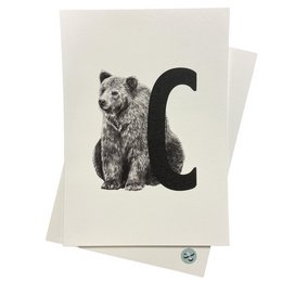 A greeting card featuring a black and white illustration of a bear sitting next to the letter "C".