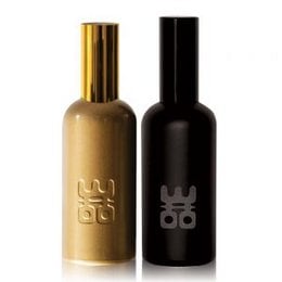Two glass bottles with gold and black labels, containing a room spray or body mist product. The bottles have a sleek, minimalist design with the brand name "Woo" prominently displayed.