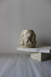 Glossy, handmade vase with a unique, irregular shape and textured surface. Made of ceramic material.