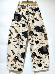 Cream and black cow print high-waist wide-leg jeans with abstract splatter pattern design.