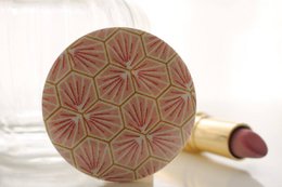  A round, pink pocket mirror with a decorative floral pattern on the surface.