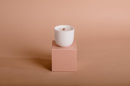 Tall, round white wax candle on a pink pedestal.