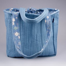 A medium-sized tote bag made of blue organic cotton with a floral pattern. The bag has a pleated design and a sturdy shoulder strap for comfortable carrying.