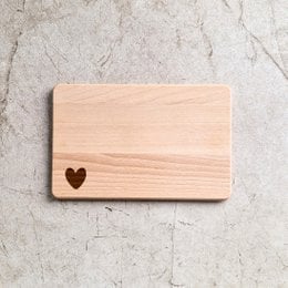 Wooden cutting board with heart-shaped design, suitable for kitchen use.