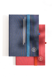 Vegan bio-leather notebook in medium, ruby, large, tanzanite sizes. Features a sleek design with a pen holder and colorful accents.