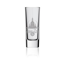 A small, clear glass shot glass with a decorative design featuring a castle or cathedral-like structure. The glass has a simple, elegant appearance suitable for serving liqueurs or other small drinks.