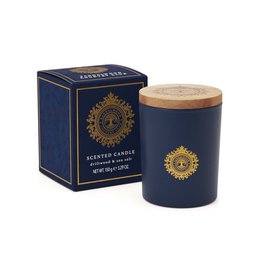 A tall, round candle in a navy blue container with a gold sun design. The candle is scented with driftwood and sea salt, creating a calming and natural aroma.