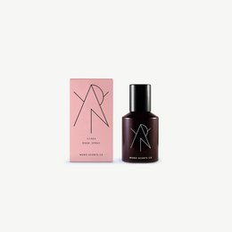 Room spray in a black bottle with a pink and black label. The spray is designed to freshen up any room with its pleasant scent.