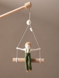 Hanging wall decor with a wooden figure in green clothing, suspended from a wooden frame.
