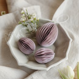  Paper Easter eggs in soft pink color, arranged on a white plate with lily of the valley flowers.