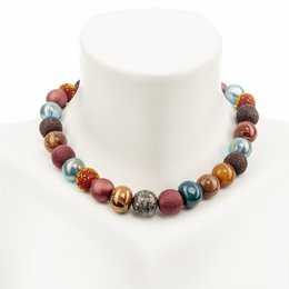 Colorful beaded necklace with a mix of materials including glass, stone, and metal beads in various shapes and sizes. The necklace features a range of warm, earthy tones including red, brown, and blue.