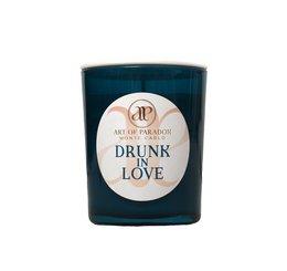Tall, round, teal-colored scented candle with a white label that says "Drunk in Love". The candle has a wooden wick.