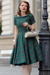  A green and red plaid swing dress with a fitted bodice and a flared skirt. The dress has a high neckline and short sleeves.