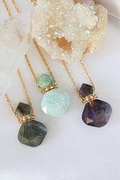 Luxury mini crystal bottles with 24K natural crystals, available in amethyst, amazonite, and labradorite. Pendant necklaces with unique gemstone shapes and colors.
