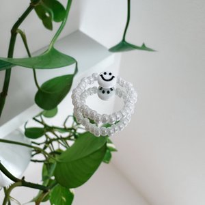Parelring gemaakt van witte glaskralen met een smiley in het wit