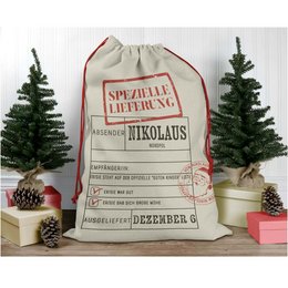 A large, gray sack with red text that reads "SPEZIELLE LIEFERUNG NIKOLAUS" (Special Delivery Santa Claus). The sack appears to be made of a durable, canvas-like material and has a drawstring closure at the top. The sack is surrounded by Christmas trees and other holiday decorations, suggesting it is a gift bag or sack for holding Christmas presents.