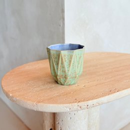 Small stoneware cup with a minted lilac color and geometric pattern design.