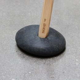A single stone stand for a toothbrush holder, made of a smooth, dark stone base and a wooden handle.