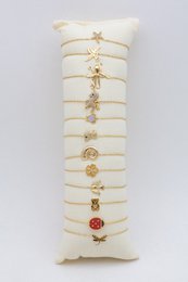 Présentoir coussin en tissu écru comprenant un lot de 12 bracelets fins en maille forçat dorée déjà installés.