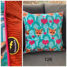  Cushion cover with a vibrant fox print design on a teal background. The cushion features a repeating pattern of foxes surrounded by colorful arches.