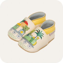  Soft leather baby slippers in a beige color with a train and palm tree design. The slippers have a comfortable and flexible sole, and are available in sizes from 0-6 months to 3-4 years.