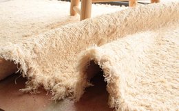 Handwoven rug crafted from upcycled materials, featuring a soft, textured surface and natural beige tones.