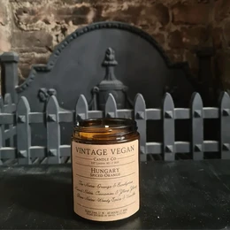 Vintage vegan soy wax candle with spiced orange scent, in a glass jar with a black label featuring a vintage design.