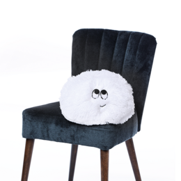 A plush, white cushion with a cute face design, sitting on a black velvet chair. The cushion appears to be a decorative accent piece for a child's room or nursery.
