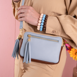 Sky blue leather shoulder bag with tassel detail, compact structured design, gold hardware accents