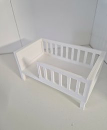 White wooden junior bed for dolls, with slatted sides and a simple, minimalist design.