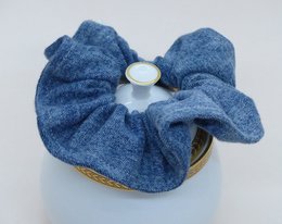 Denim blue scrunchie with a soft, textured fabric and a simple, elegant design.