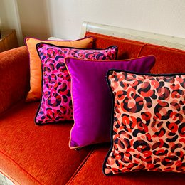 Vibrant pink and orange leopard print cushions with a plush, textured surface. The cushions feature a bold, eye-catching pattern that would add a stylish, modern touch to any living space.