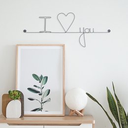 "Wall sticker with the text 'I love you' in a stylized wire design."
The image shows a wall sticker with a wire design that spells out "I love you". The design features a heart shape and the text "I love you" in a minimalist, stylized wire format. This wall sticker would be suitable for home decor, expressing affection, or as a romantic gift.