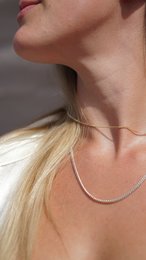  A delicate silver or gold chain necklace with a simple, elegant design. The necklace features a thin, minimalist chain that complements a variety of outfits.