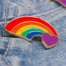 Colorful rainbow heart-shaped pin with a pride flag design. Made of metal with a shiny finish, suitable for attaching to clothing, bags, or accessories.