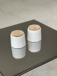 White decorative vessels with cork lids, available in marble brown and marble gray colors.