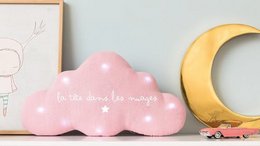 A pink cloud-shaped musical nightlight with stars, designed for a baby's room. The nightlight is made of linen material and has a "head in the clouds" theme.