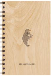 A wooden poster with a small bear graphic and the text "BON ANNIVERSAIRE!" (Happy Birthday in French). The poster has a spiral binding and a light wood grain background.