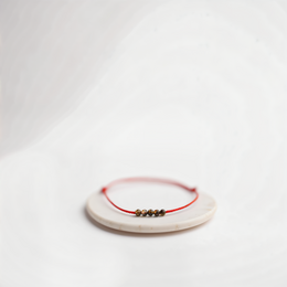 A delicate crimson-colored beaded bracelet with a simple, elegant design.