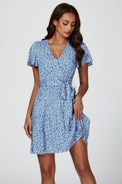 A floral print mini dress in a blue color with a tiered wrap design and short sleeves. The dress has a v-neck and a tie waist for a flattering fit.
