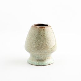 Ceramic matcha beater holder in blue, black, and white colors. Cylindrical shape with a wide base and narrow top. Suitable for holding and storing a matcha whisk or beater.