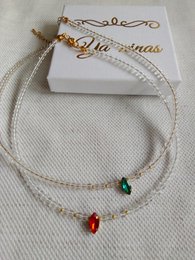 This XMAS SET includes a woven necklace with a double strand design. The necklace features red and green beads, creating a festive holiday look. The set also includes matching earrings with green beads.