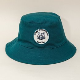 "Teal bucket hat with raccoon logo, suitable for children ages 6-12 months, 1-3 years, and 4-7 years."