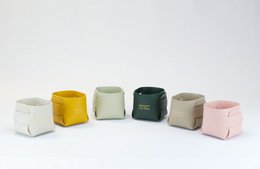 Small storage basket in various colors including curry, sand, sage, rose, cream, and jungle green. Compact cube shape with woven texture.