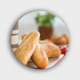  A round wall circle featuring a close-up image of baguettes on a wooden board.