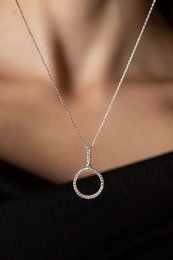  A delicate, circular pendant necklace made of silver-toned metal with a simple, minimalist design.